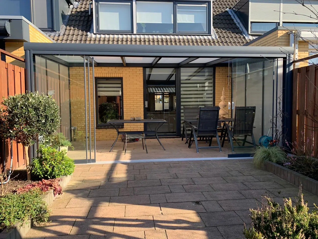 Aluminium veranda met glazen schuifwanden aan een zonnig terras